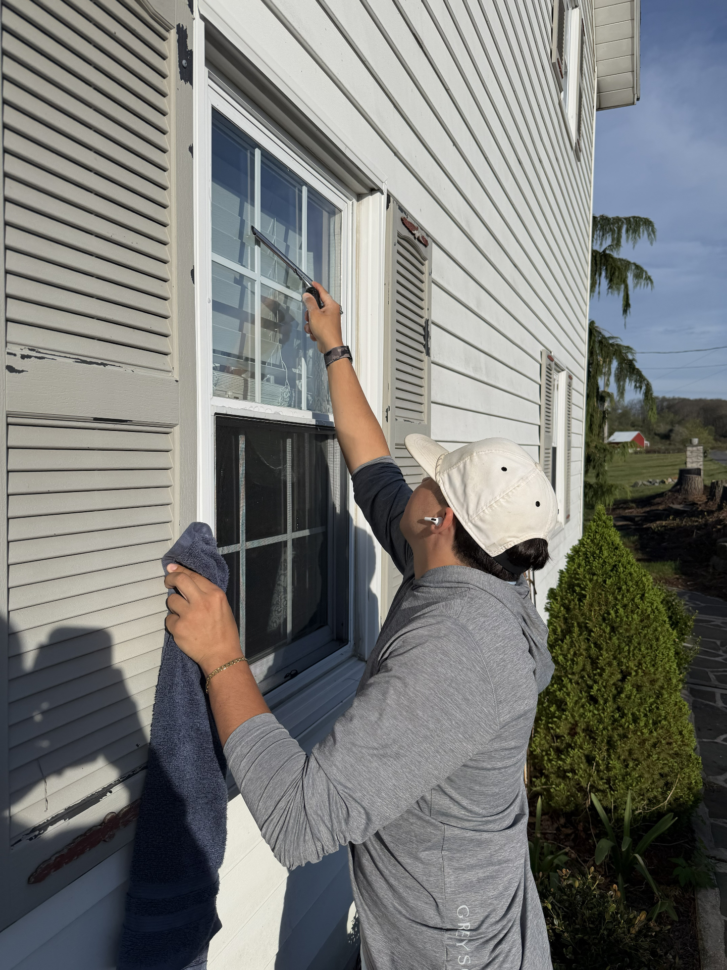 Christian cleaning an exterior window with a squeegee